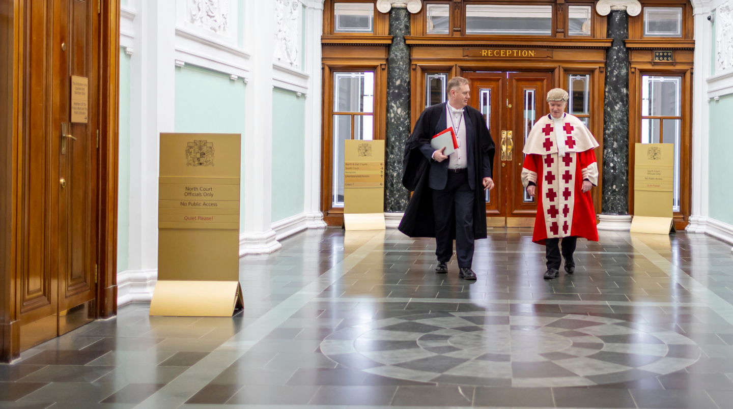 Two men in legal attire walking down a hallway